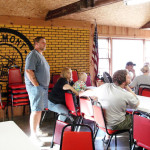 A man stands in a casual meeting room with seated attendees.