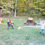 A family enjoying a barbecue in a wooded area during fall.