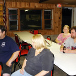A group of people sitting at a table inside a wooden room.