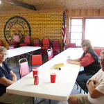 Three women sitting around a long table in a community room.
