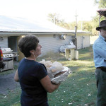 Woman carrying food trays outdoors during a casual gathering.