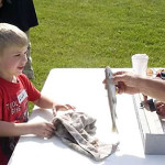 Boy at fishing derby, has fish measured
