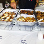 Buffet trays filled with various cooked meats at a catered event.