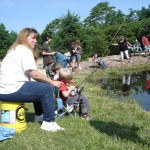 People fishing by a lakeside on a sunny day.