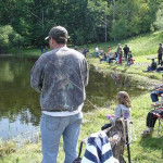 People enjoy fishing by a peaceful lakeside on a sunny day.