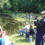 People fishing by a pond on a sunny day.