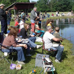 People fishing by a pond on a sunny day.