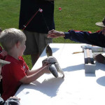 A child with a prosthetic arm catches a fish at a fishing event.