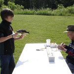 Two people playing a tabletop game outdoors on a sunny day.