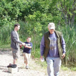 An older man walking on a forest path with a young boy and a younger man.