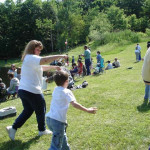 A woman and a boy playing a game outdoors with a crowd watching.