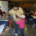 Man presenting an award to a young girl in a community hall.