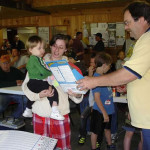 A woman holding a child receives a certificate from a man at a community event.