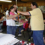 A man awards a young girl in a crowded indoor event.