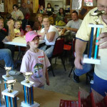 Children and adults gathered for a trophy award event indoors.