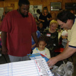 People gathered around a table with a chart, focusing on an activity.
