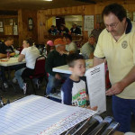 Man and boy interacting in a busy indoor gathering.