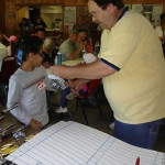 Man giving a wristband to a girl at a community event.