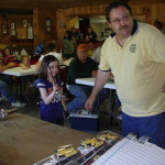 Man demonstrating slot car racing to a young girl in a cozy room.