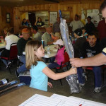 A girl holds a wrapped item at a crowded indoor event.