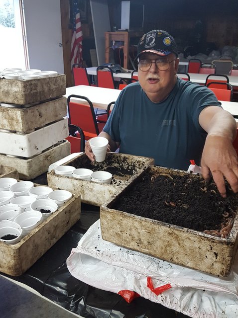 A man sitting in front of boxes filled with dirt.