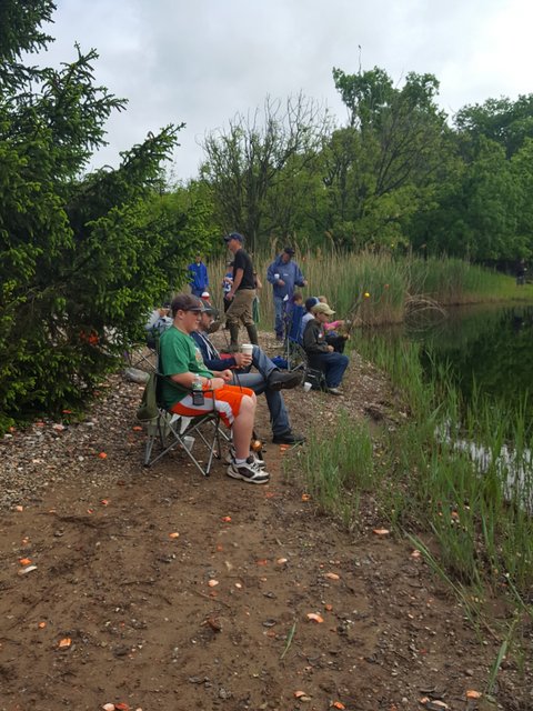 A group of people sitting on the ground near water.