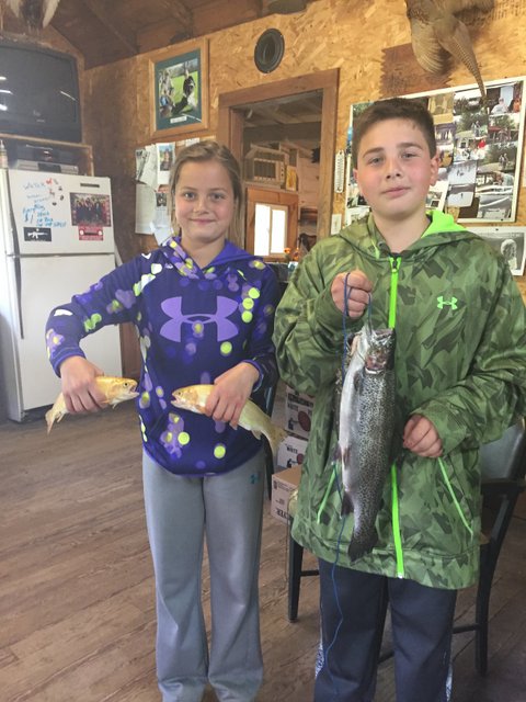 Two kids holding a fish in their hands.