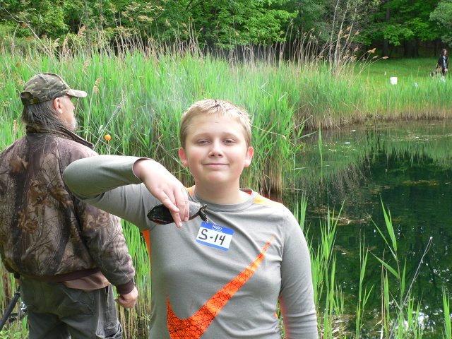 A boy is holding onto the handle of his fishing rod.