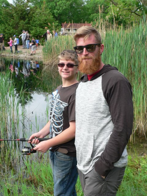 Two men standing next to each other holding fishing rods.