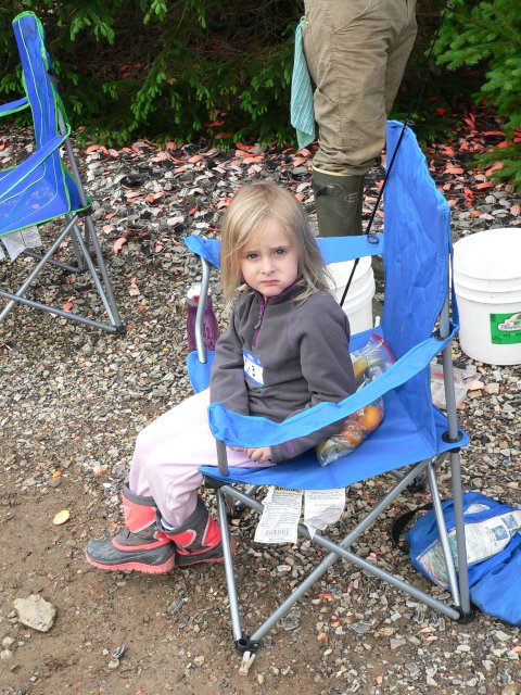 A little girl sitting in a blue folding chair.