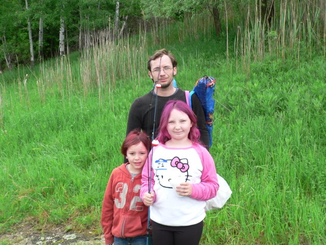 A man and two girls standing in the grass.