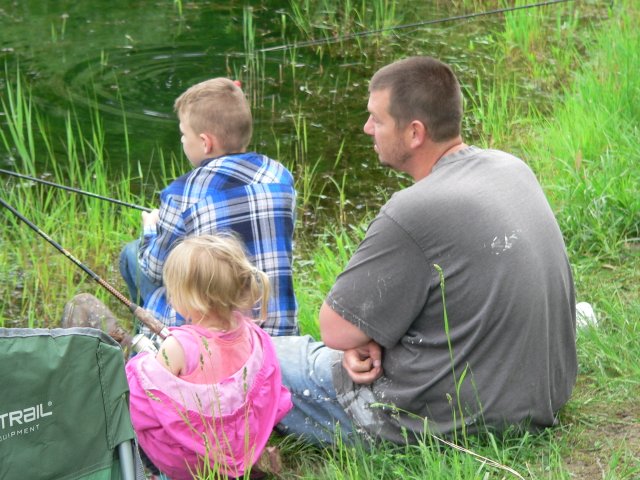 A man and two children sitting in the grass.