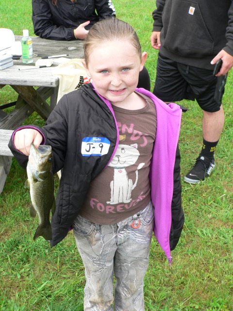 A little girl holding a fish in her hand.