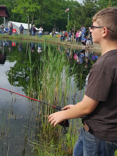 A man standing in front of some water holding a fishing rod.