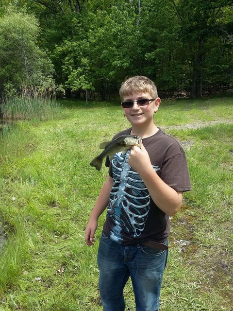 A young man holding a fish in his hand.