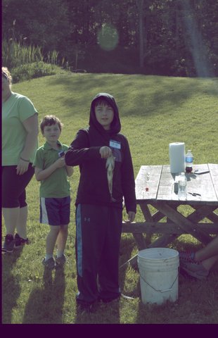 A boy holding a pole in front of a table.