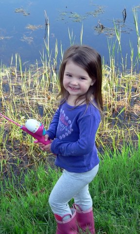 A little girl holding a pink fishing pole.