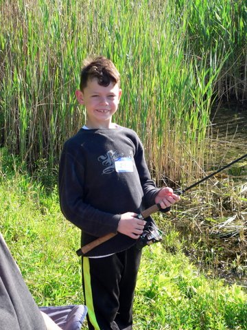A young boy holding a fishing rod in his hands.