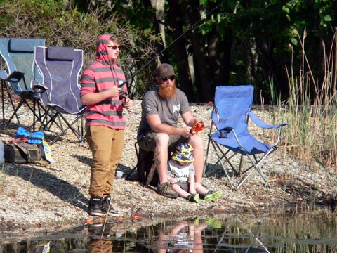 Two people fishing in a pond with chairs