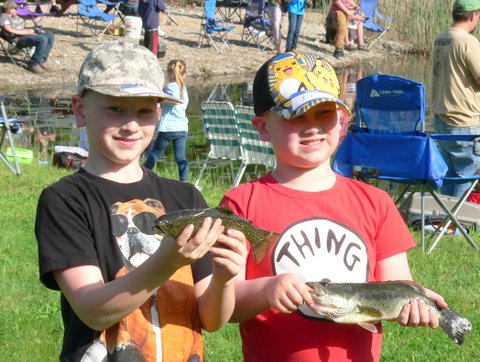Two boys holding fish in their hands while standing next to each other.