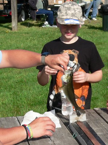 A boy holding a fish while standing next to another person.