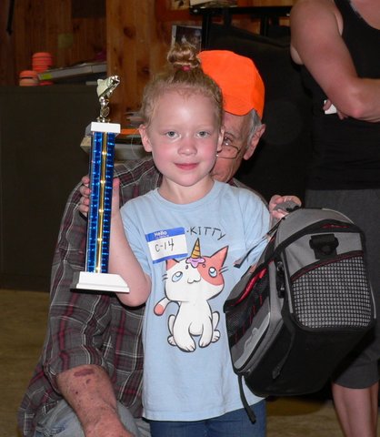 A little boy holding a trophy and wearing an award.