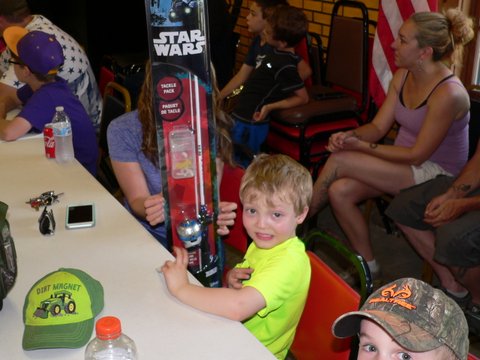A boy holding up a toy at an event.