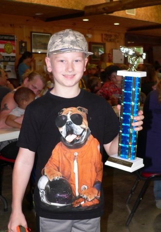 A boy holding up a trophy with an image of a dog on it.