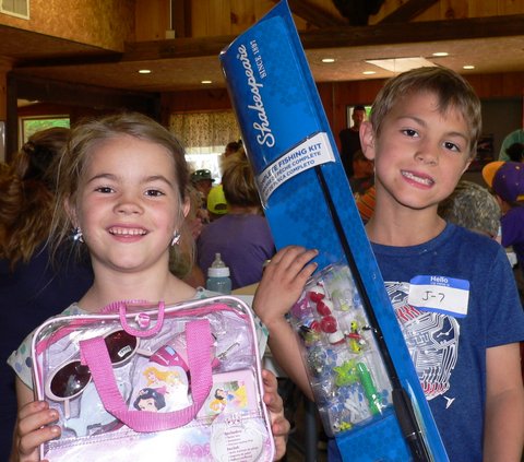 Two children holding up their bags at a convention.