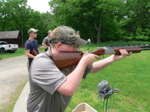 A man holding a rifle while standing next to another person.