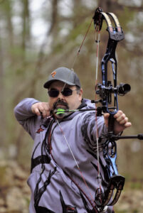 A man is holding his bow and aiming at the target.