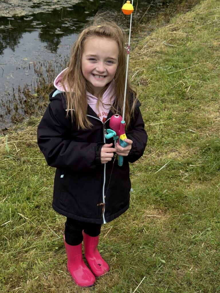 Young girl holding a fishing pole in a black coat